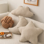 Cloud, star, moon, bolster and knot cushions grouped on a bed